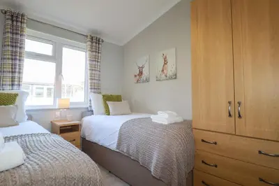 a bedroom with two beds and a large window at 4 Meadow Retreat in Liskeard