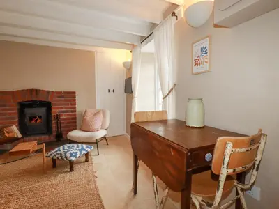 a living room with a desk and a fireplace at Waterside Cottage in Truro