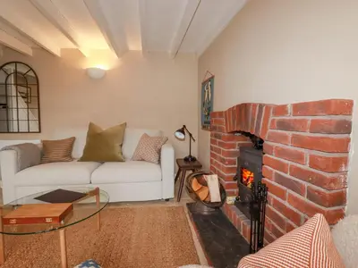 a living room with a couch and a brick fireplace at Waterside Cottage in Truro