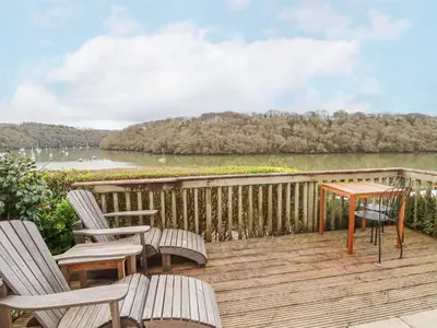 a deck with chairs and a table and a lake at Waterside Cottage in Truro