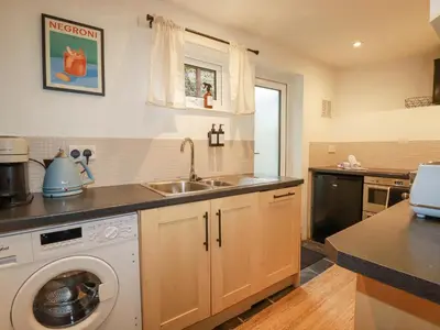 a kitchen with a sink and a washing machine at Waterside Cottage in Truro
