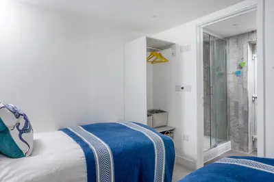 a bedroom with a bed and a shower at Loe Cottage in Helston