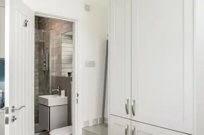 a white bathroom with a sink and a mirror at Loe Cottage in Helston