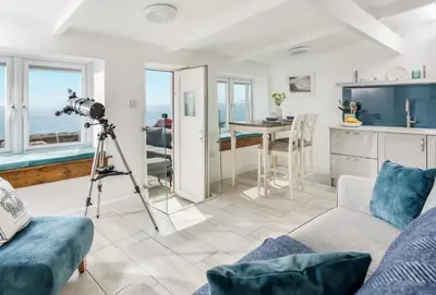 a camera on a tripod in a living room with the ocean at Loe Cottage in Helston