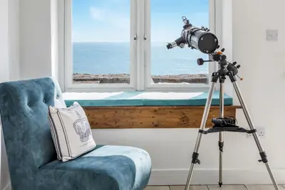 a camera on a tripod next to a chair and a window at Loe Cottage in Helston