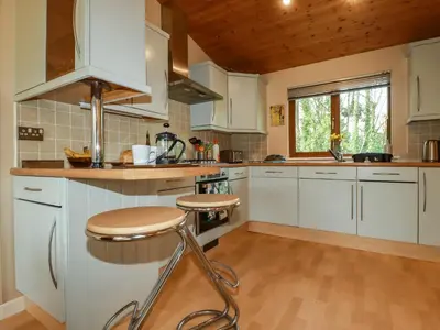 a kitchen with white cabinets and a wooden ceiling at 4 The Glade in Wadebridge