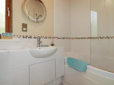 a white bathroom with a sink and a mirror at 4 The Glade in Wadebridge