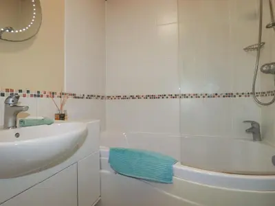 a white bathroom with a sink and a bath tub at 4 The Glade in Wadebridge
