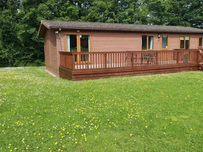 a small cabin with a deck in a field of grass at 4 The Glade in Wadebridge