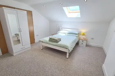 a bedroom with a bed with a mirror and a skylight at Stable Barn Apartment in Saint Breward