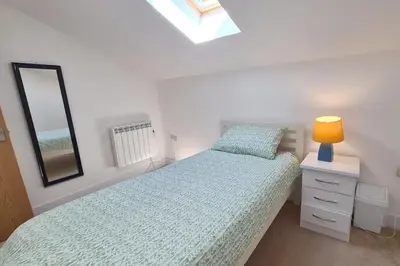 a bedroom with a bed with a lamp and a mirror at Stable Barn Apartment in Saint Breward
