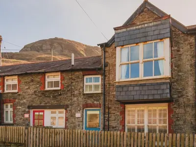 a brick house with a fence and a mountain in the background at Apartment Tintagel Sea view by Interhome in Treknow