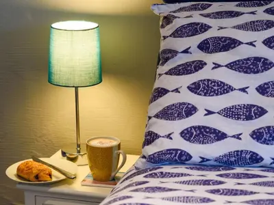 a bed with a table with a lamp and a cup of coffee at Holiday Home Stargazey Cottage by Interhome in Mevagissey