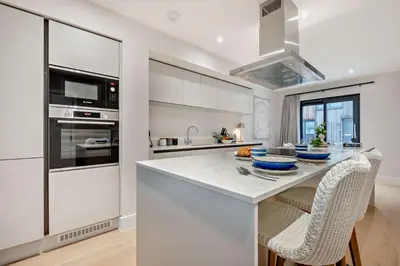 a kitchen with white cabinets and a kitchen island with chairs at 2 Bed in Harlyn Bay oc-s28921 in St Merryn