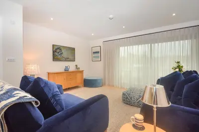 a living room with blue furniture and a large window at 2 Bed in Harlyn Bay oc-s28921 in St Merryn