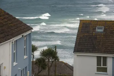 a view of the ocean from between two houses at 6 The Point - Walk to Newquay's Beaches - Free WiFi and Parking in Newquay