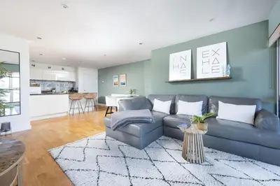 a living room with a blue couch and a kitchen at 6 The Point - Walk to Newquay's Beaches - Free WiFi and Parking in Newquay