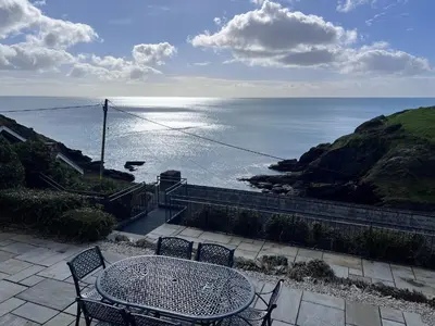 a table and chairs with a view of the ocean at Cottages at the Lugger in Portloe