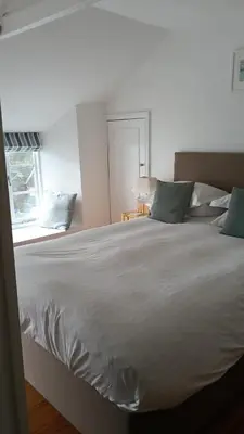 a large white bed in a bedroom with a window at Cottages at the Lugger in Portloe