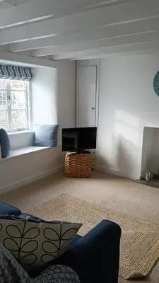 a living room with a couch and a flat screen tv at Cottages at the Lugger in Portloe