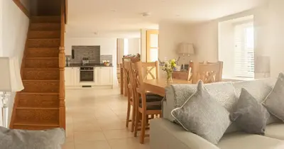 a living room and kitchen with a couch and a table at Cottages at the Lugger in Portloe