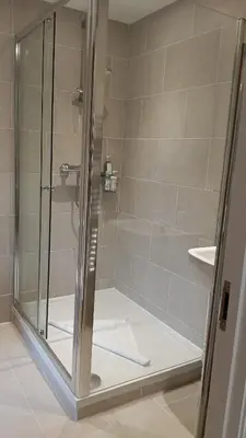 a bathroom with a shower with a glass door at Cottages at the Lugger in Portloe