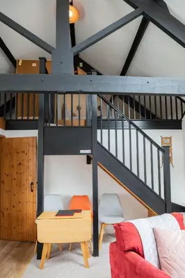 a living room with a staircase and a red couch at Treworgie Barton - Trespaddick in Bude