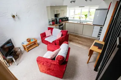 a living room with a red couch and a kitchen at Treworgie Barton - Trespaddick in Bude