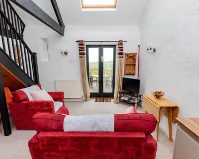 a living room with two red couches and a tv at Treworgie Barton - Trespaddick in Bude