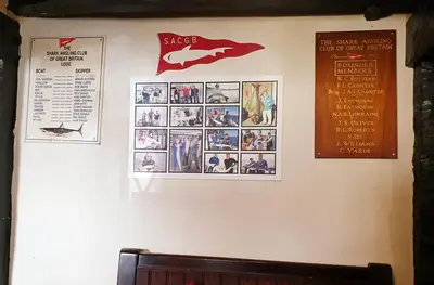 a wall with pictures and posters on it at Jolly Sailor Inn in Looe