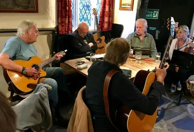 a group of people sitting around a table playing guitars at Jolly Sailor Inn in Looe