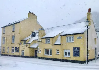 a building covered in snow in the middle of a street at Jolly Sailor Inn in Looe