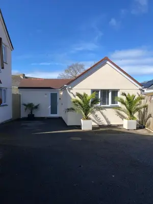 a white house with two palm trees in a driveway at Sunnyside Retreat in St Ives