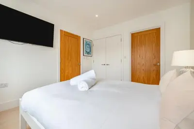 a white bedroom with a white bed and a flat screen tv at 4 Bed in St. Merryn oc-t29153 in St Merryn