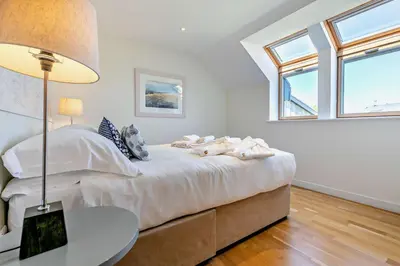 a bedroom with a bed with a table and windows at 3 Bed in Trevone oc-c29020 in Padstow
