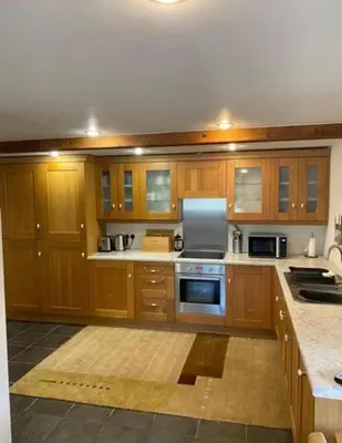 a kitchen with wooden cabinets and a stove top oven at Trelowen Cottage in Callington