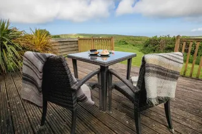 a table and two chairs sitting on a deck at Treworgie Barton - Braddon in Bude