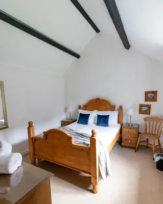 a bedroom with a wooden bed with blue pillows at Treworgie Barton - Braddon in Bude