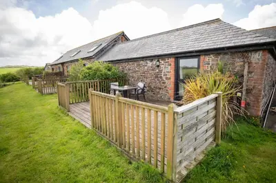 a house with a wooden deck and a fence at Treworgie Barton - Braddon in Bude