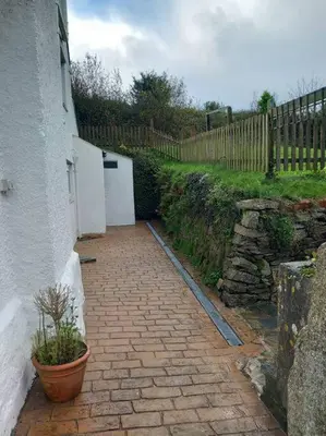 a brick walkway with a building and a fence at Rural Cornish farmhouse in Liskeard