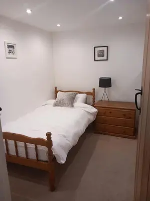 a bedroom with a bed and a dresser and a lamp at Rural Cornish farmhouse in Liskeard