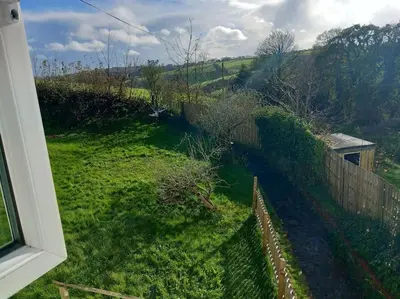 a view from a window of a yard with a fence at Rural Cornish farmhouse in Liskeard