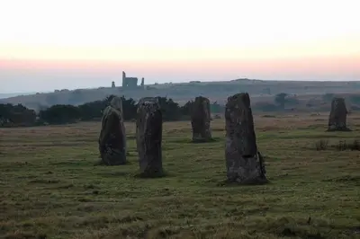 a field with stone formations in a field with a castle in the background at Rural Cornish farmhouse in Liskeard