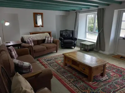 a living room with a couch and a coffee table at Rural Cornish farmhouse in Liskeard