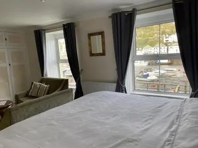 a bedroom with a bed and a large window at Little Mainstone Guest House in Looe