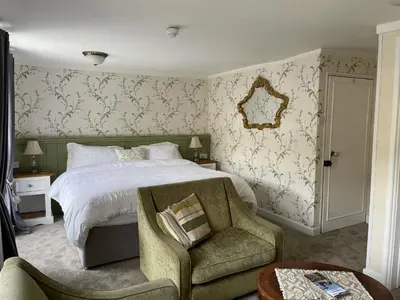 a bedroom with a bed and a chair at Little Mainstone Guest House in Looe