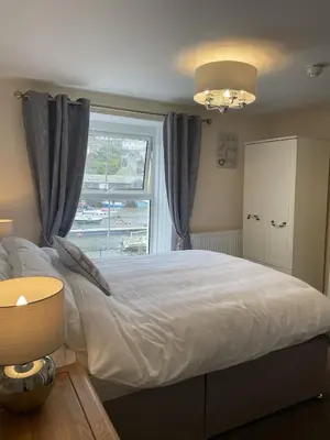 a bedroom with a large bed with a window at Little Mainstone Guest House in Looe