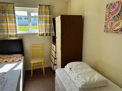 a small bedroom with a bed and a chair at Bungalow 19 in Poundstock
