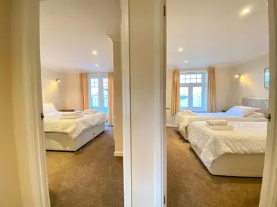 a bedroom with three beds and a doorway to a room at 4 Bedroom House at Atlantic Reach-Newquay-Cornwall in Newquay