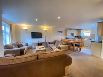 a living room with a couch and a table and a kitchen at 4 Bedroom House at Atlantic Reach-Newquay-Cornwall in Newquay